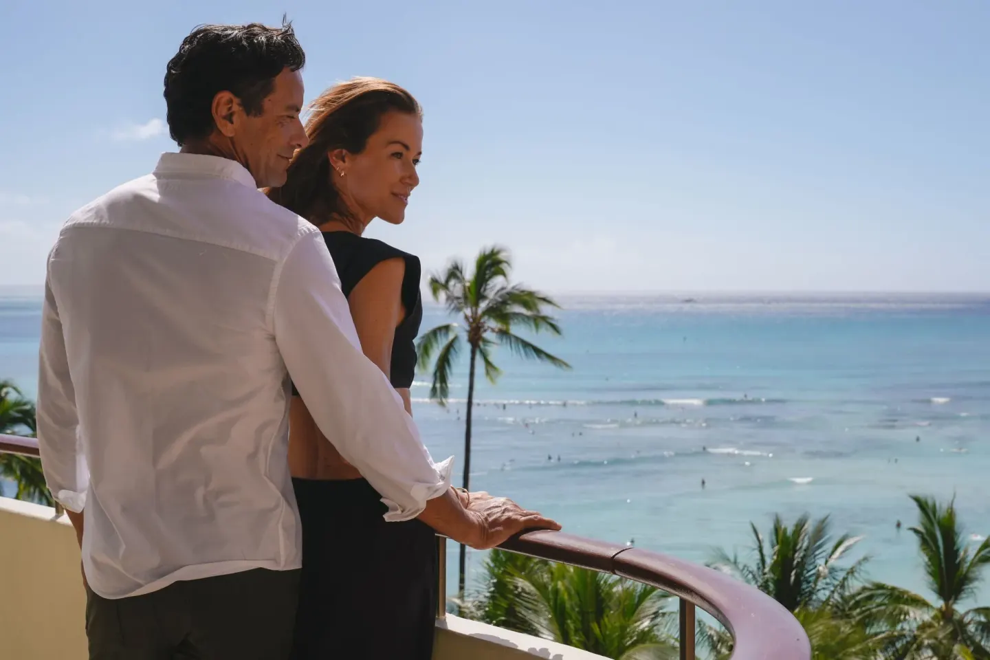 Couple on a balcony overlooking Waikiki Beach at The Royal Hawaiian, Waikiki.
