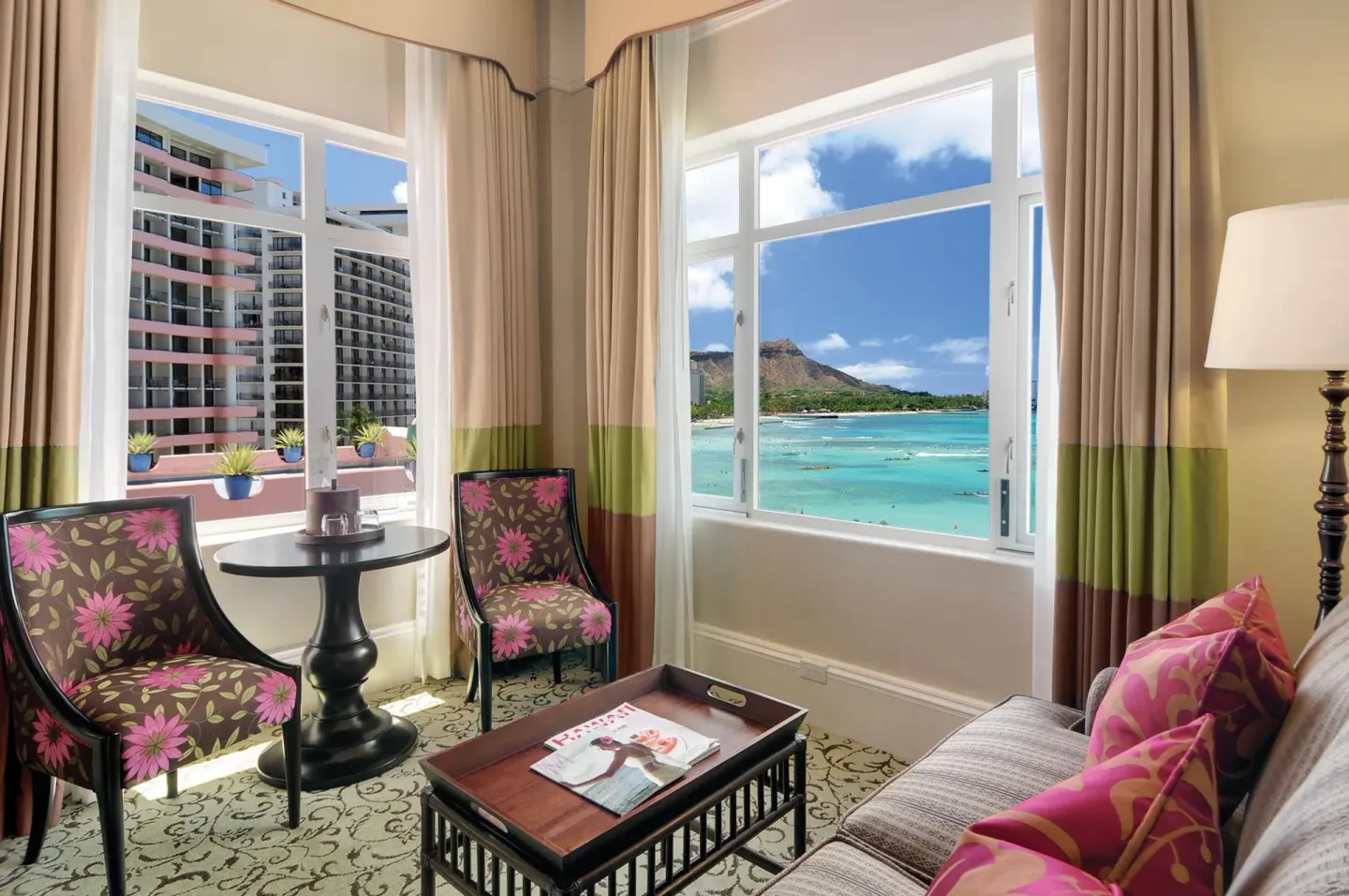 Ocean-view sitting area with floral chairs and Waikiki windows at The Royal Hawaiian, Waikiki.