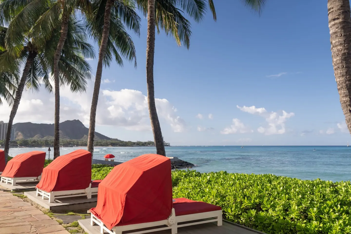 Oceanfront loungers under palms with Diamond Head beyond at The Royal Hawaiian, Waikiki.