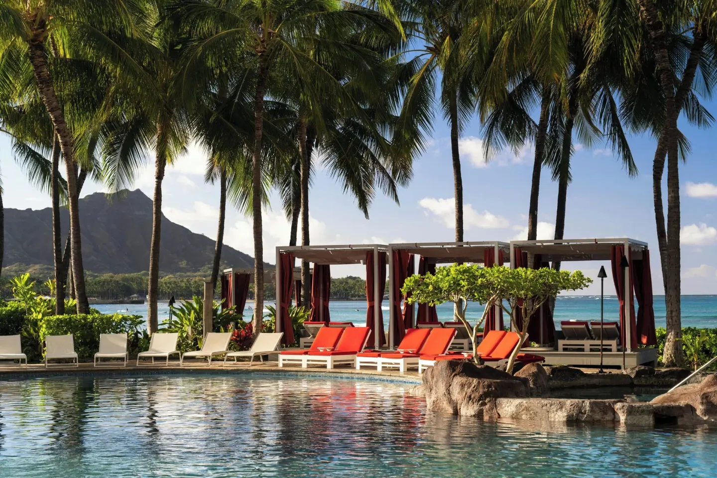 Pool cabanas and palm trees overlook Waikiki Beach at The Royal Hawaiian, Waikiki.