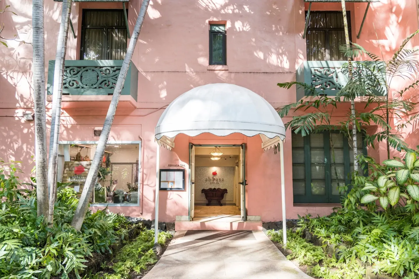 Spa entrance with a white canopy on the pink facade at The Royal Hawaiian, Waikiki.