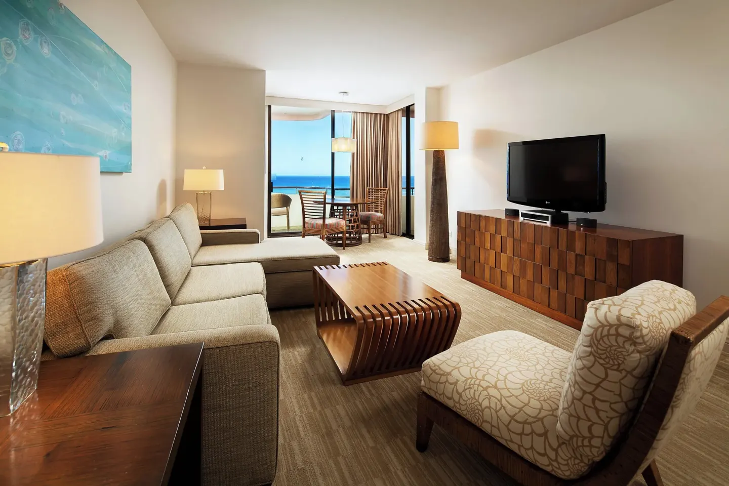 Suite living room with sofa, TV, and ocean-view balcony at The Royal Hawaiian, Waikiki.