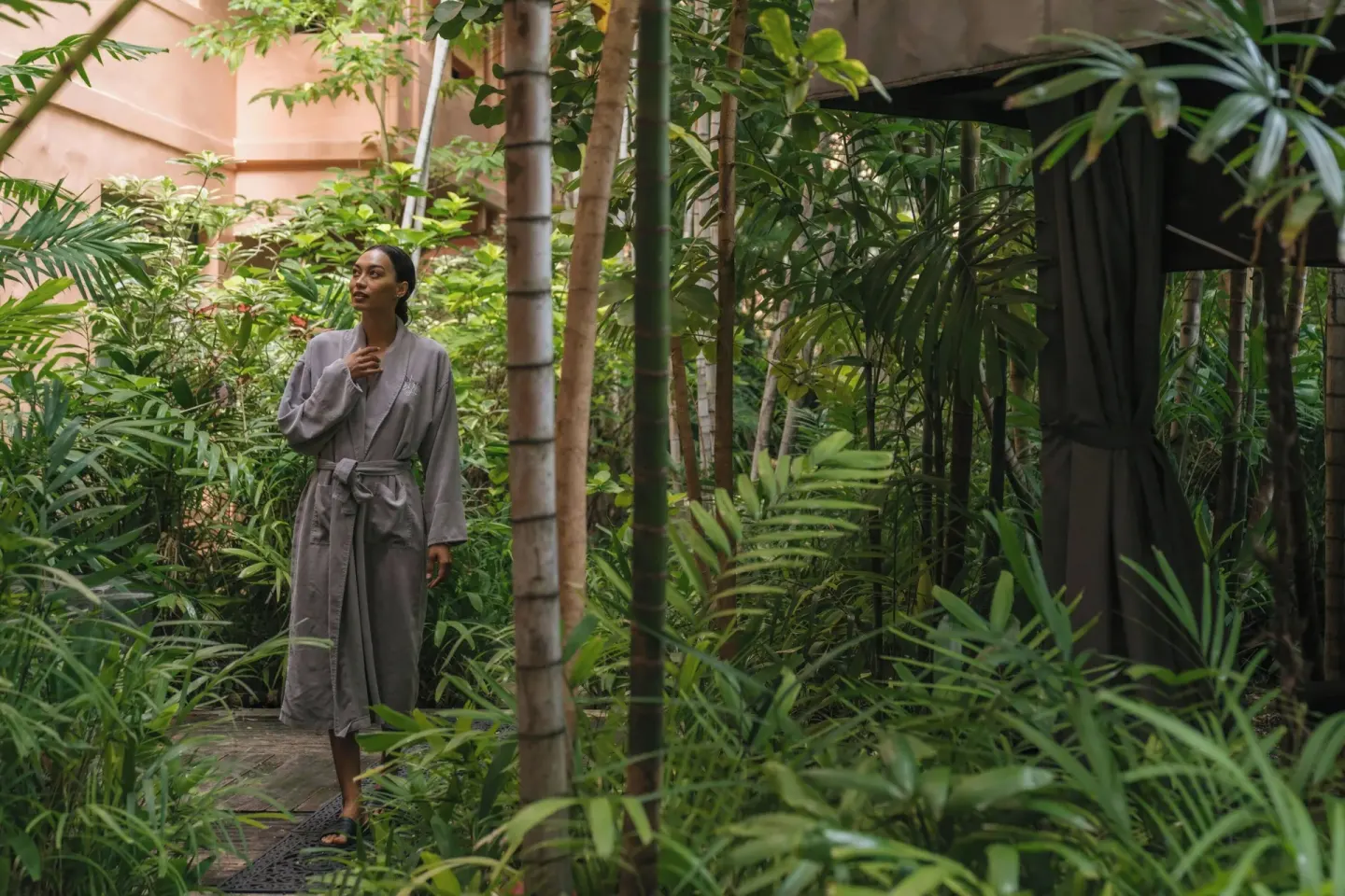 Guest in a robe walks through tropical gardens at The Royal Hawaiian, Waikiki.