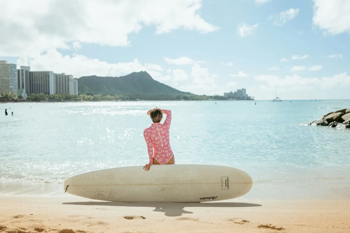 Surfer with a longboard faces Waikiki Beach and Diamond Head at The Royal Hawaiian, Waikiki.