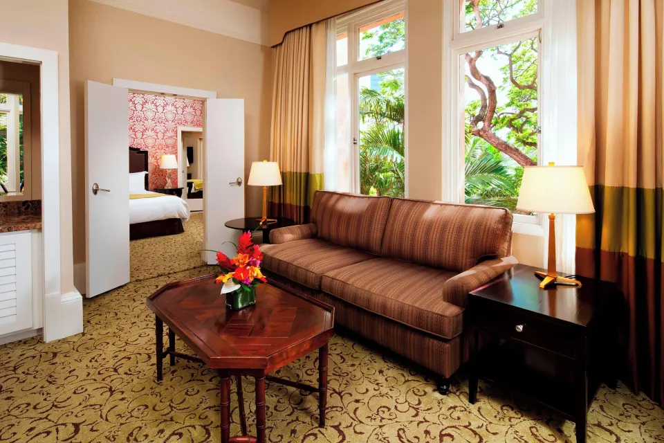 Historic Garden Jr. Suite sitting area with sofa and garden windows at The Royal Hawaiian, Waikiki.