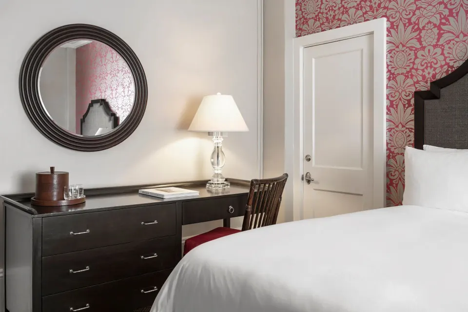 Desk, mirror, and bed in a Historic Room 1 at The Royal Hawaiian, Waikiki.
