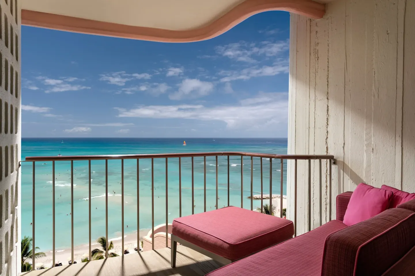 Oceanfront balcony with pink lounge seating at The Royal Hawaiian, Waikiki.