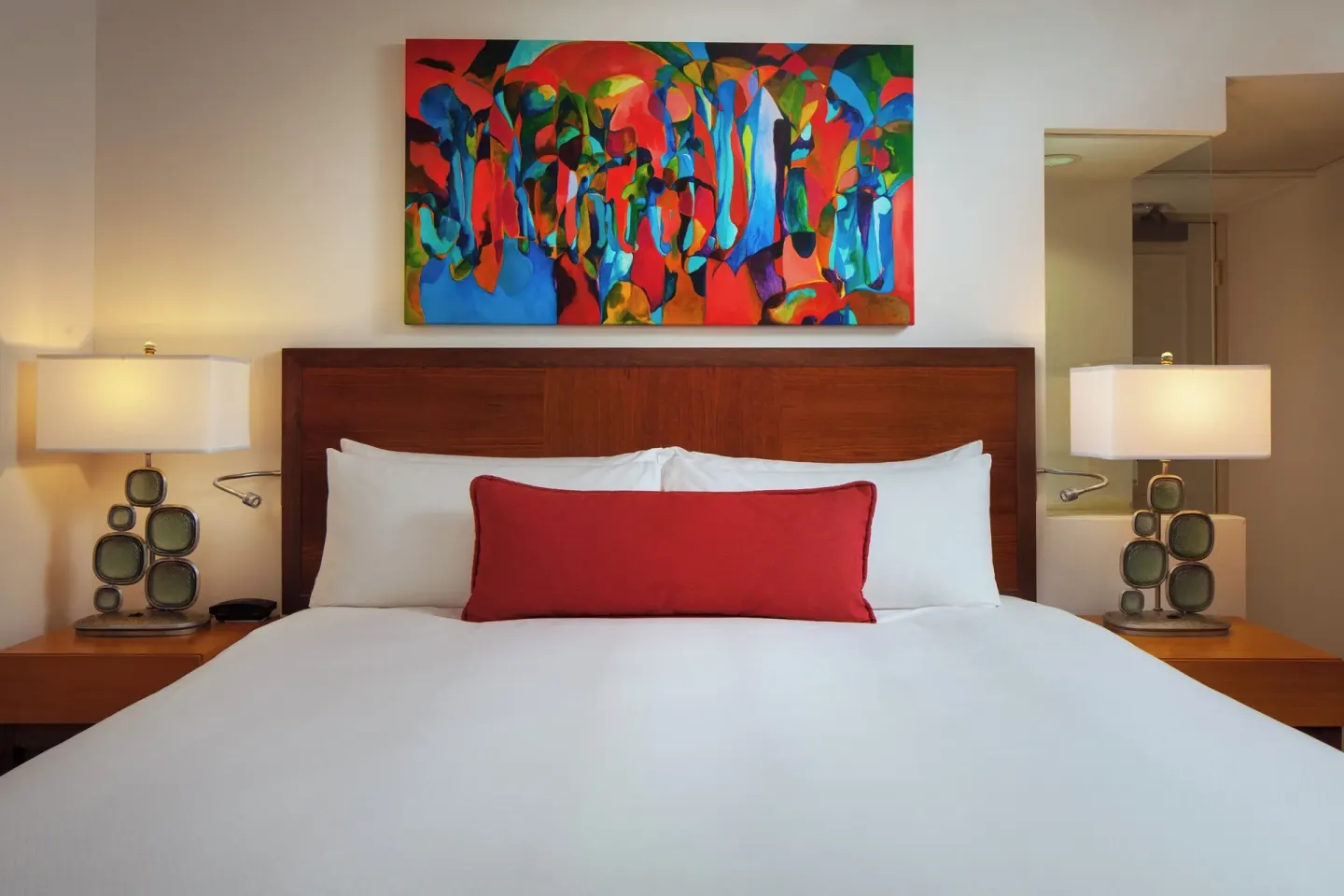 King bed with colorful artwork in a suite bedroom at The Royal Hawaiian, Waikiki.