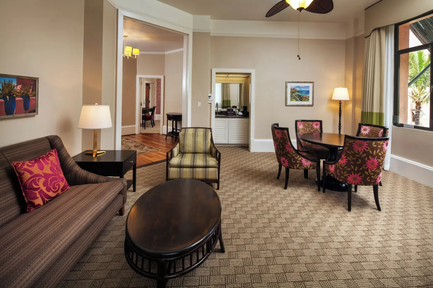 Garden View Historic Wing suite living room at The Royal Hawaiian, Waikiki with sofa, chairs and dining table.