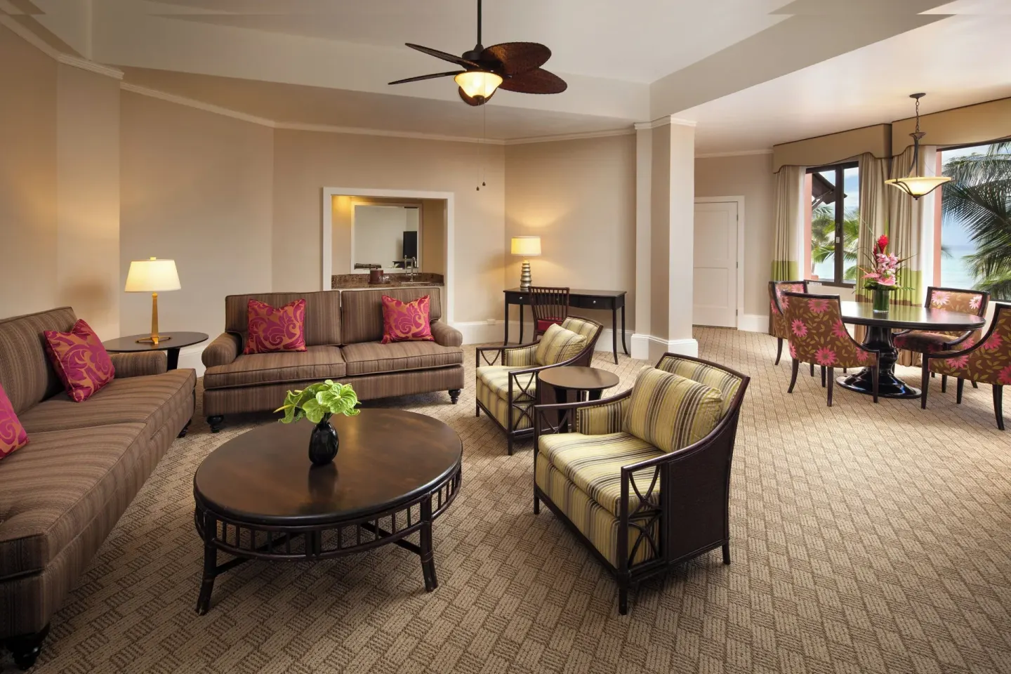 Living room with sofas, chairs, and dining area in a suite at The Royal Hawaiian, Waikiki.