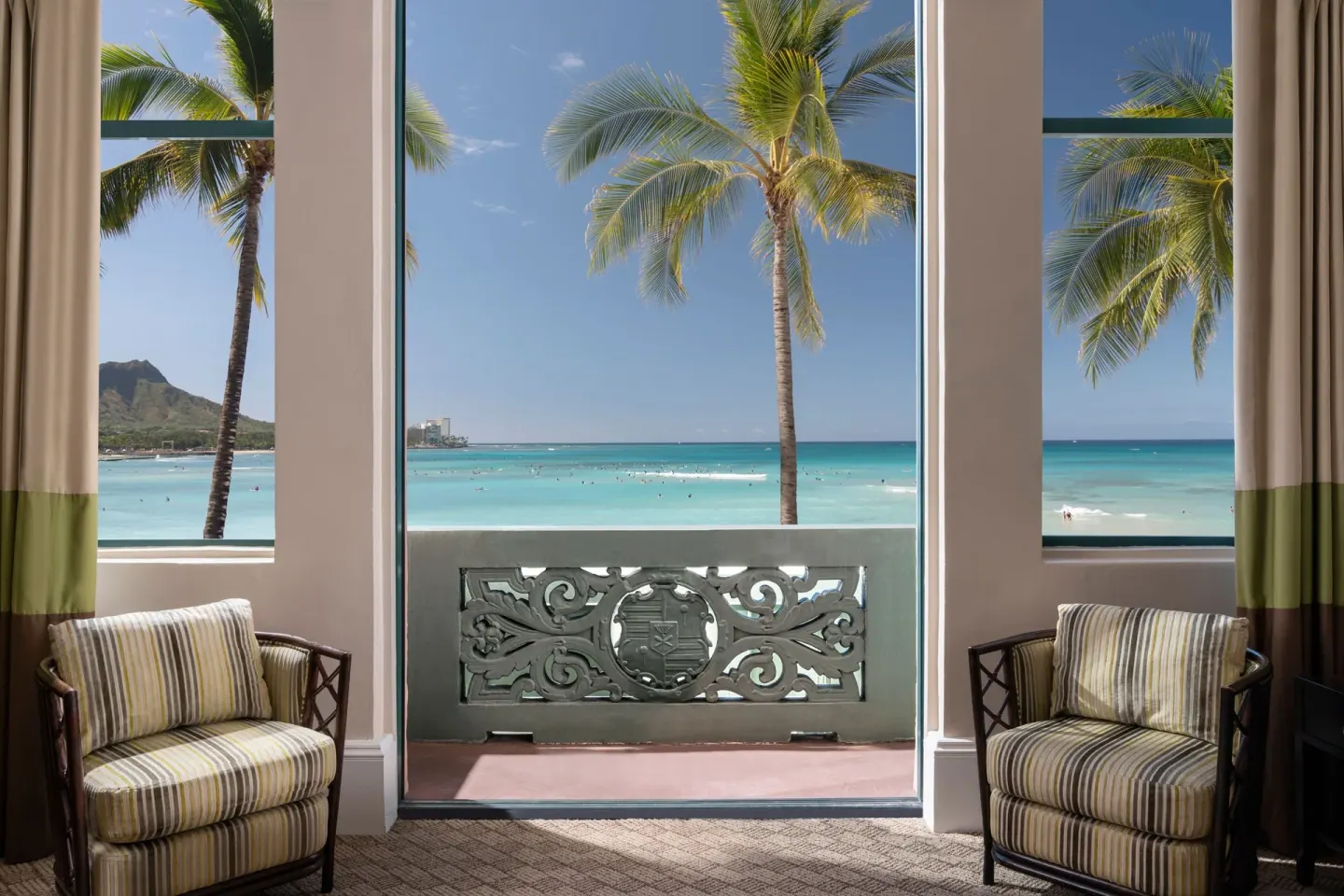 Ocean-view suite windows with balcony and chairs at The Royal Hawaiian, Waikiki.