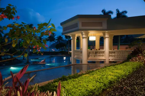 Evening poolside pavilion with columns and tropical plantings at The Royal Sonesta Kaua'i Resort Lihue.