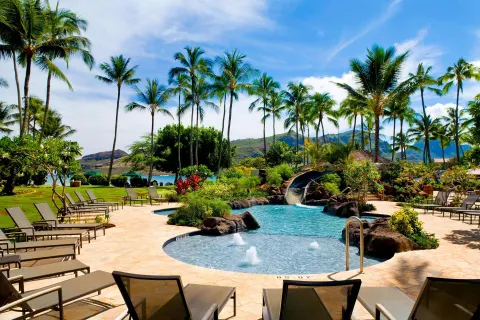 Resort pool with lounge chairs, palms and waterslide at The Royal Sonesta Kaua'i Resort Lihue.