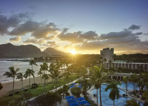 Sunset over the beach, pool, and palms at The Royal Sonesta Kaua'i Resort Lihue.