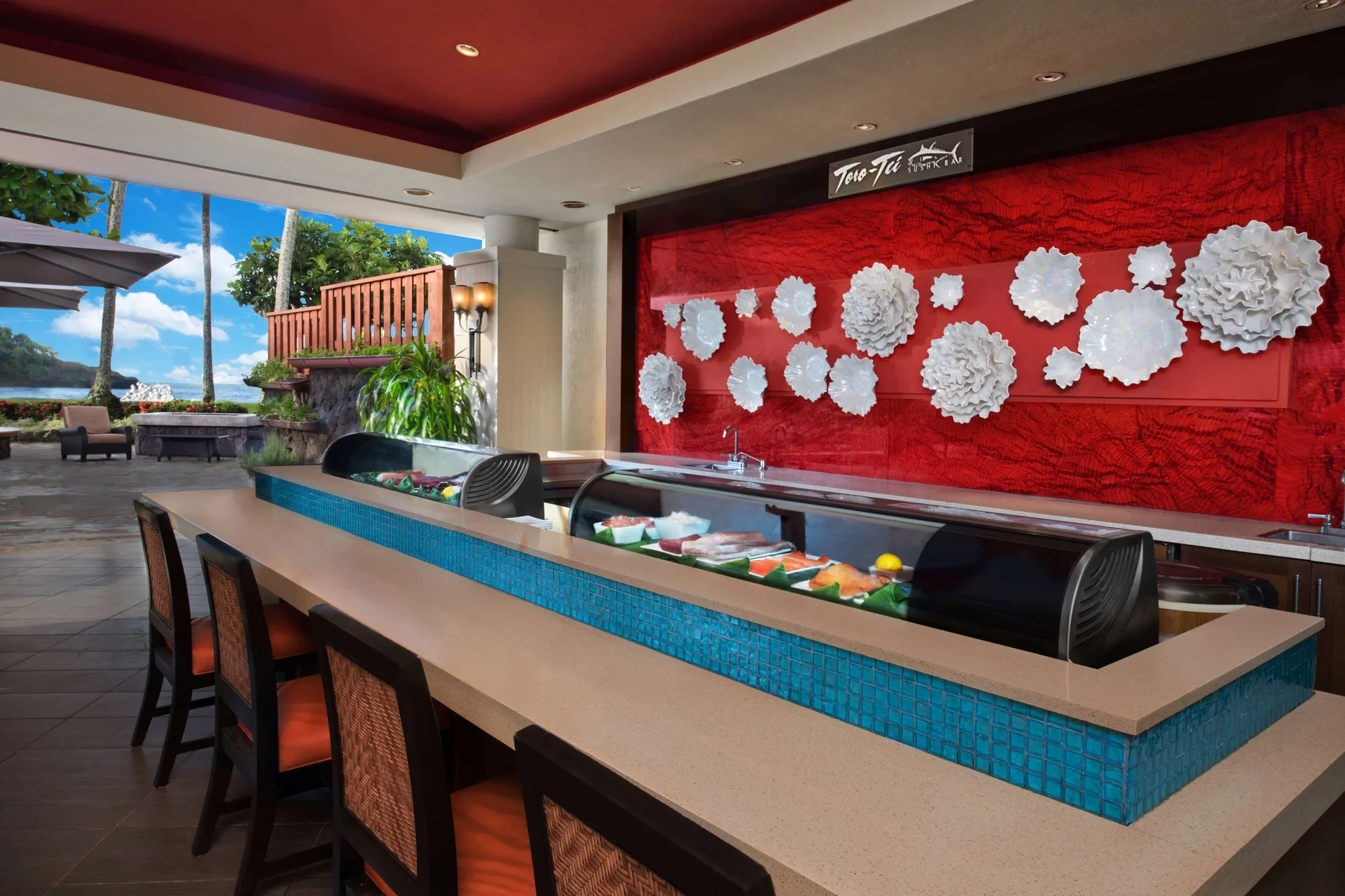 Sushi counter with red wall and ocean-facing opening at The Royal Sonesta Kaua'i Resort Lihue.