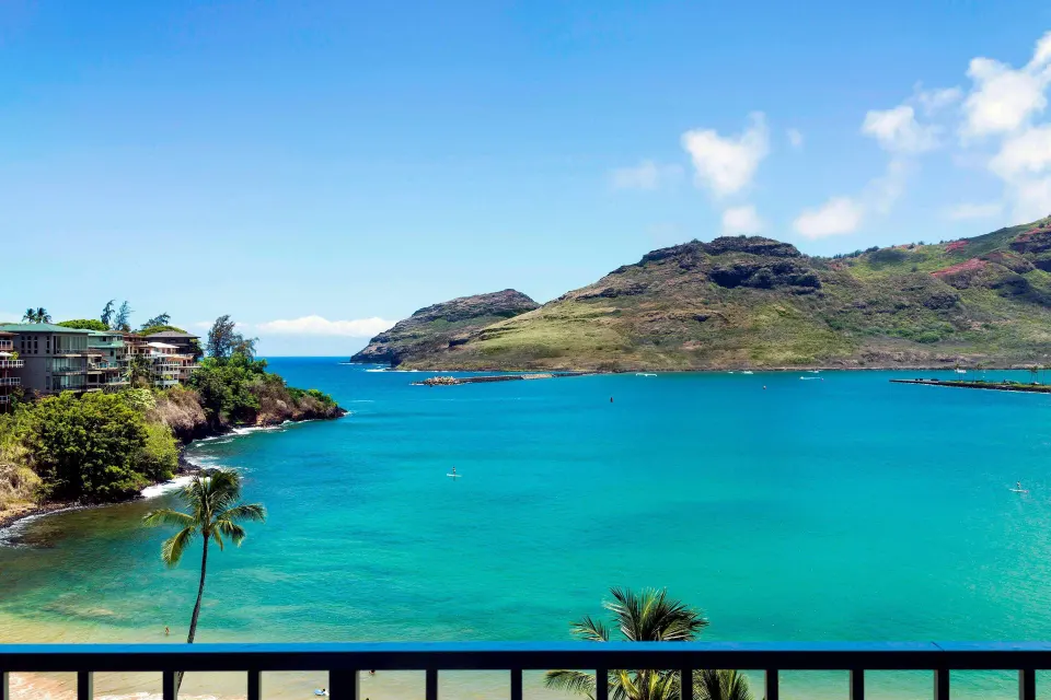 Oceanfront balcony view of turquoise bay and mountains at The Royal Sonesta Kaua'i Resort Lihue.