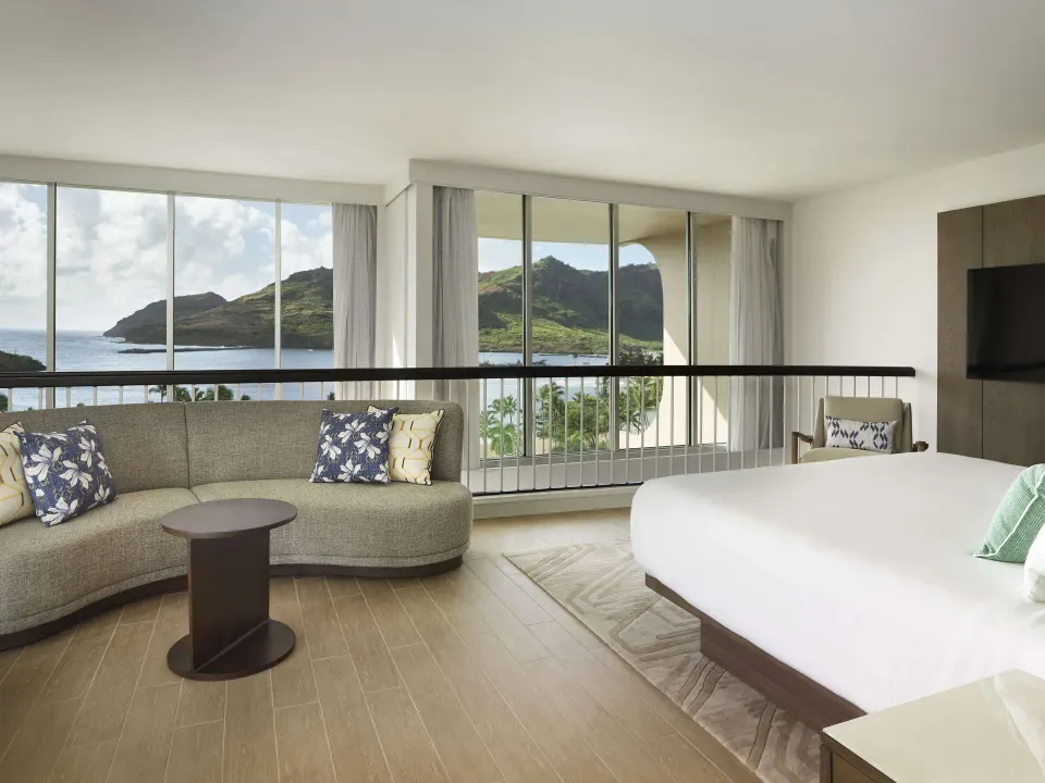 Oceanfront suite bedroom with king bed, sofa, and harbor view at The Royal Sonesta Kaua'i Resort Lihue.