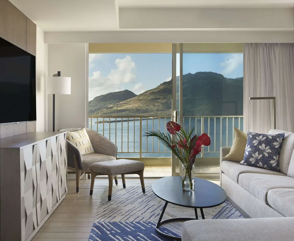 Oceanfront suite living room with sofa and balcony view at The Royal Sonesta Kaua'i Resort Lihue.