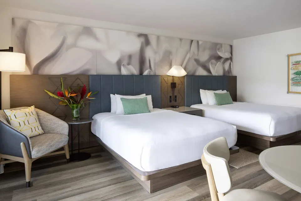 Two queen beds with seating and tropical flowers at The Royal Sonesta Kaua'i Resort Lihue.