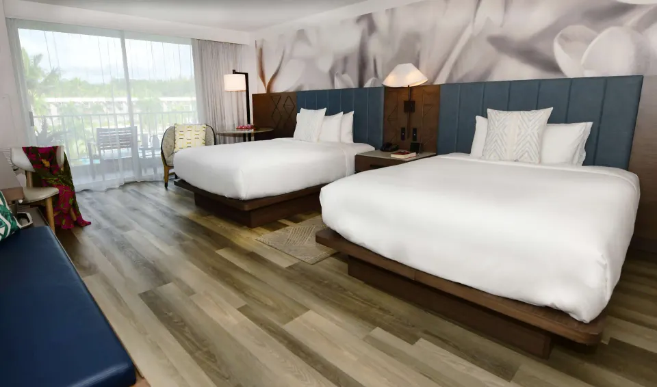 Two queen beds and balcony doors in a guest room at The Royal Sonesta Kaua'i Resort Lihue.