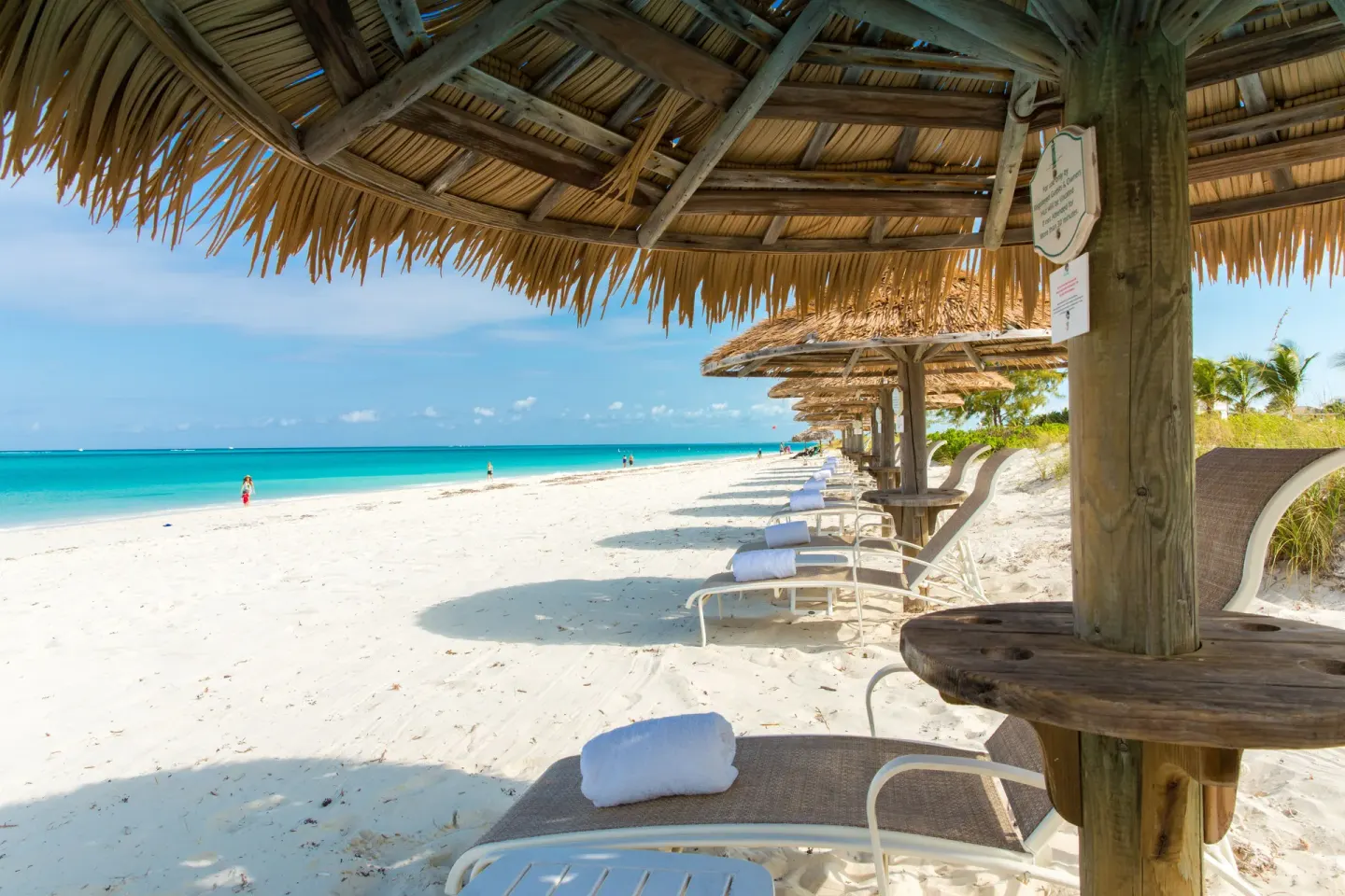 Beach loungers under thatched umbrellas at The Sands at Grace Bay.