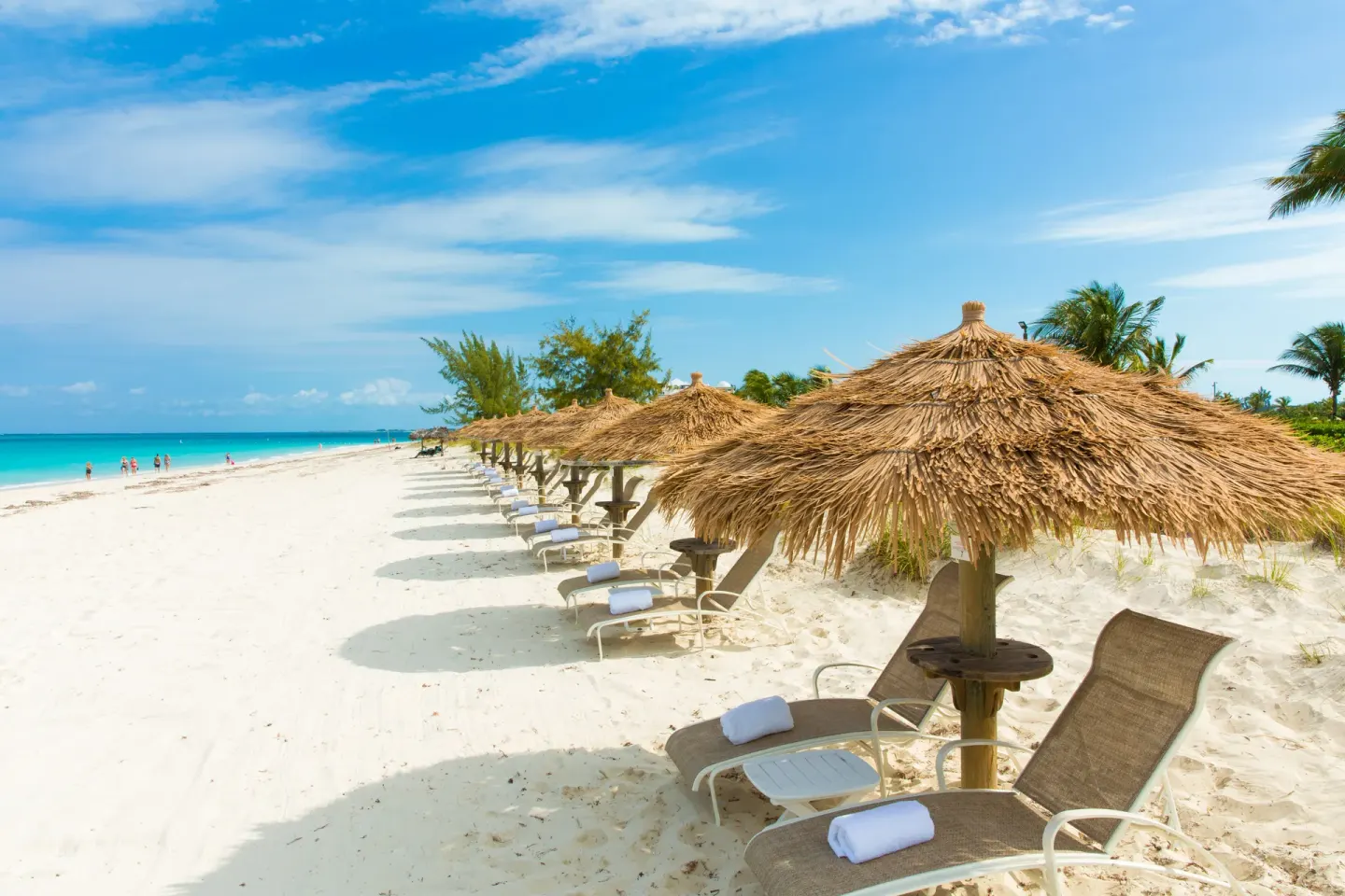 Beach loungers with thatched umbrellas along the sand at The Sands at Grace Bay.