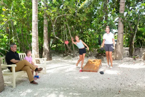 Guests play cornhole on a sandy garden path at The Sands at Grace Bay.