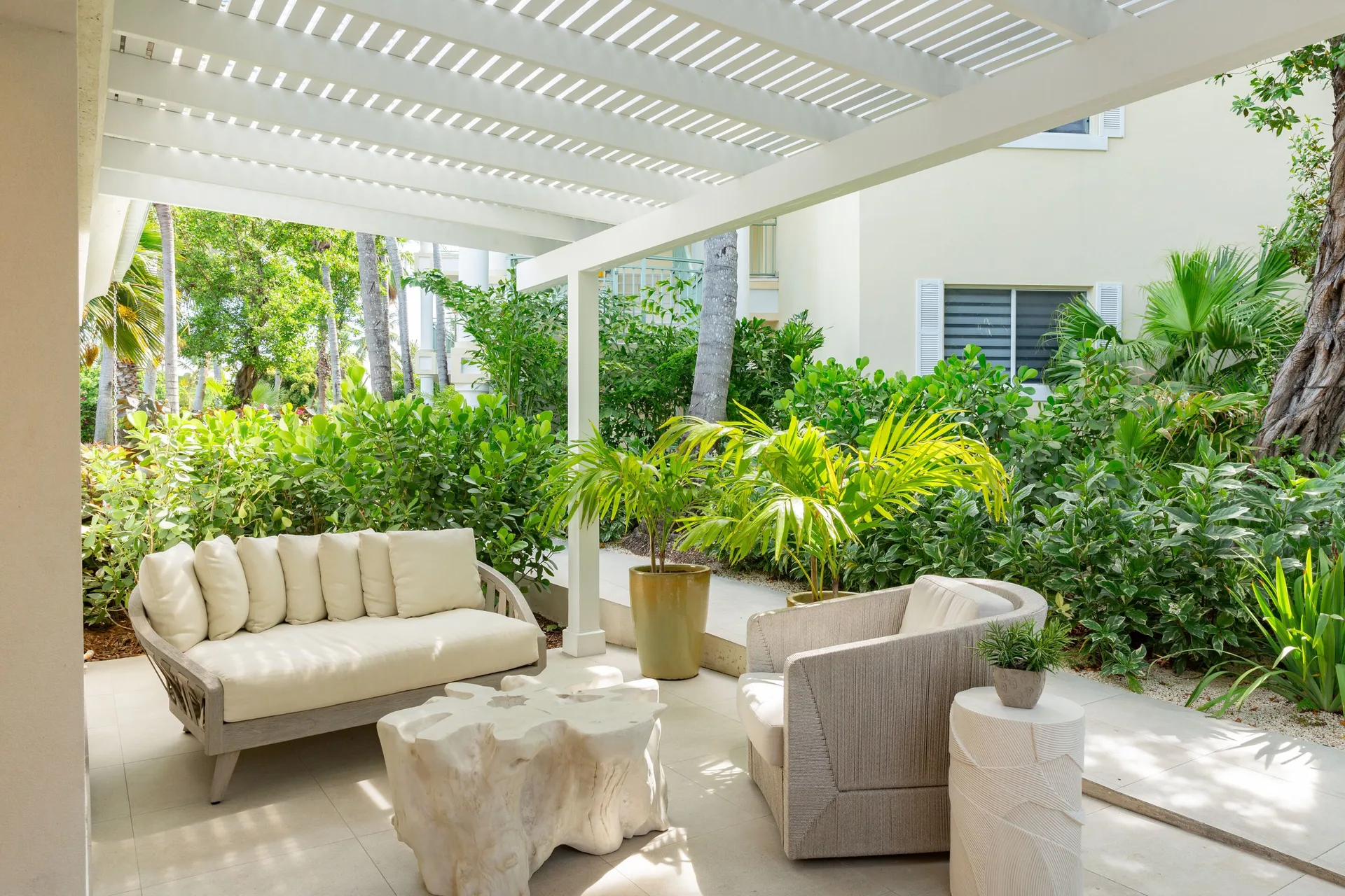 Covered garden patio with cushioned seating at The Sands at Grace Bay.