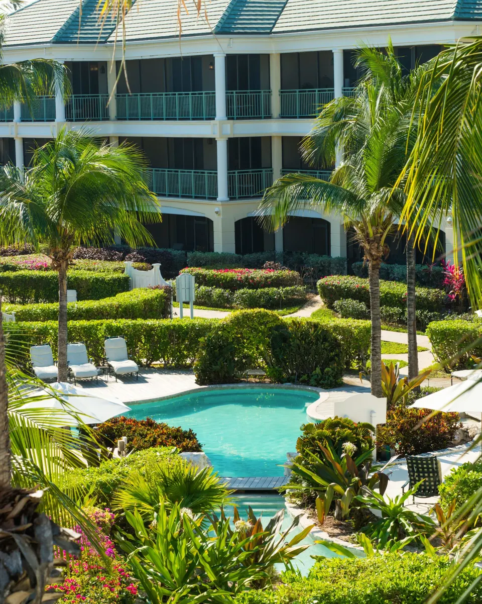 Garden pool and guest balconies among palms at The Sands at Grace Bay.