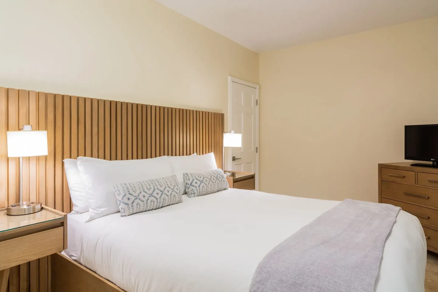 Guest room king bed with wood headboard at The Sands at Grace Bay.