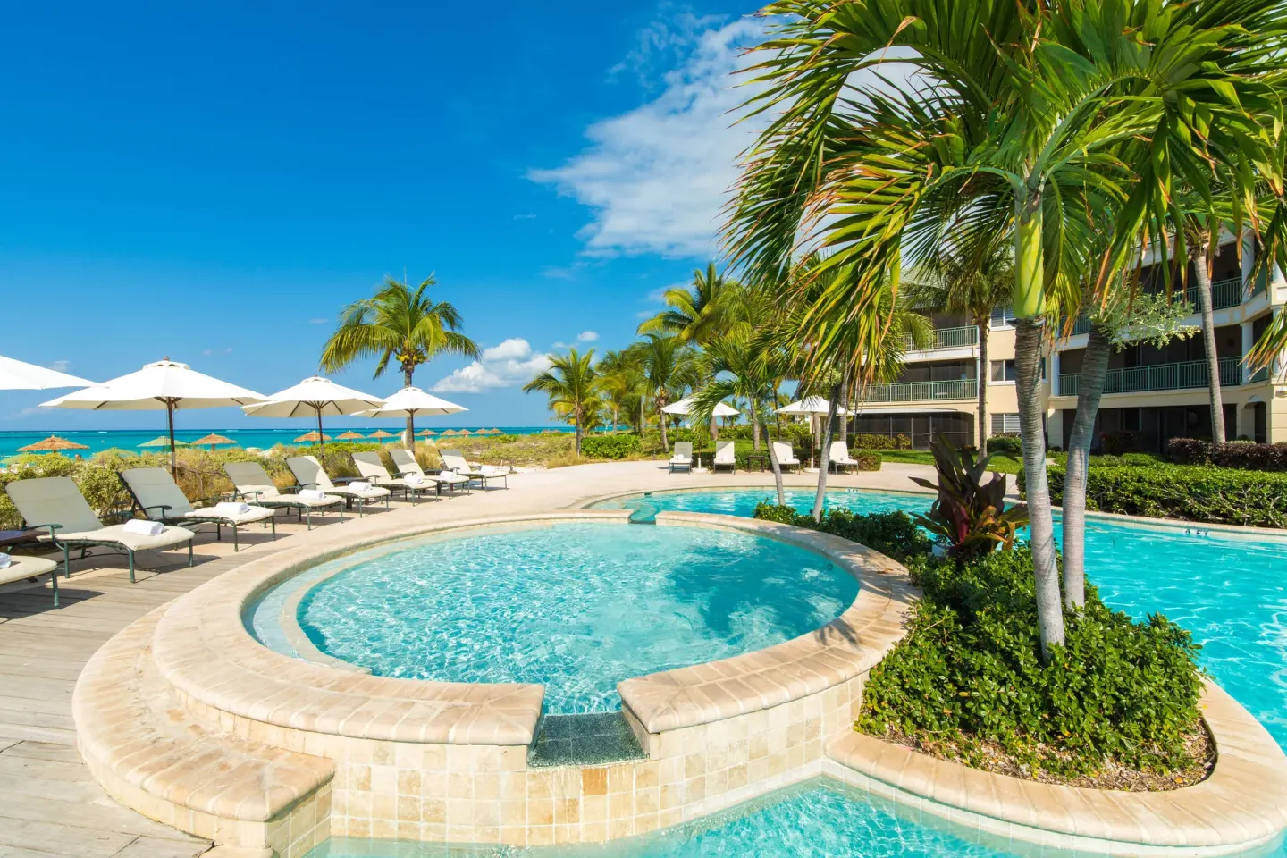 Pool deck with umbrellas near the beach at The Sands at Grace Bay.