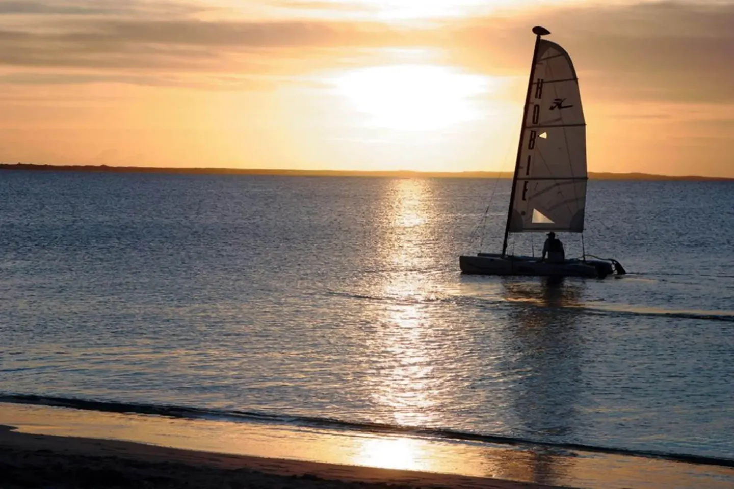 A sailboat crosses the water at sunset near The Sands at Grace Bay.