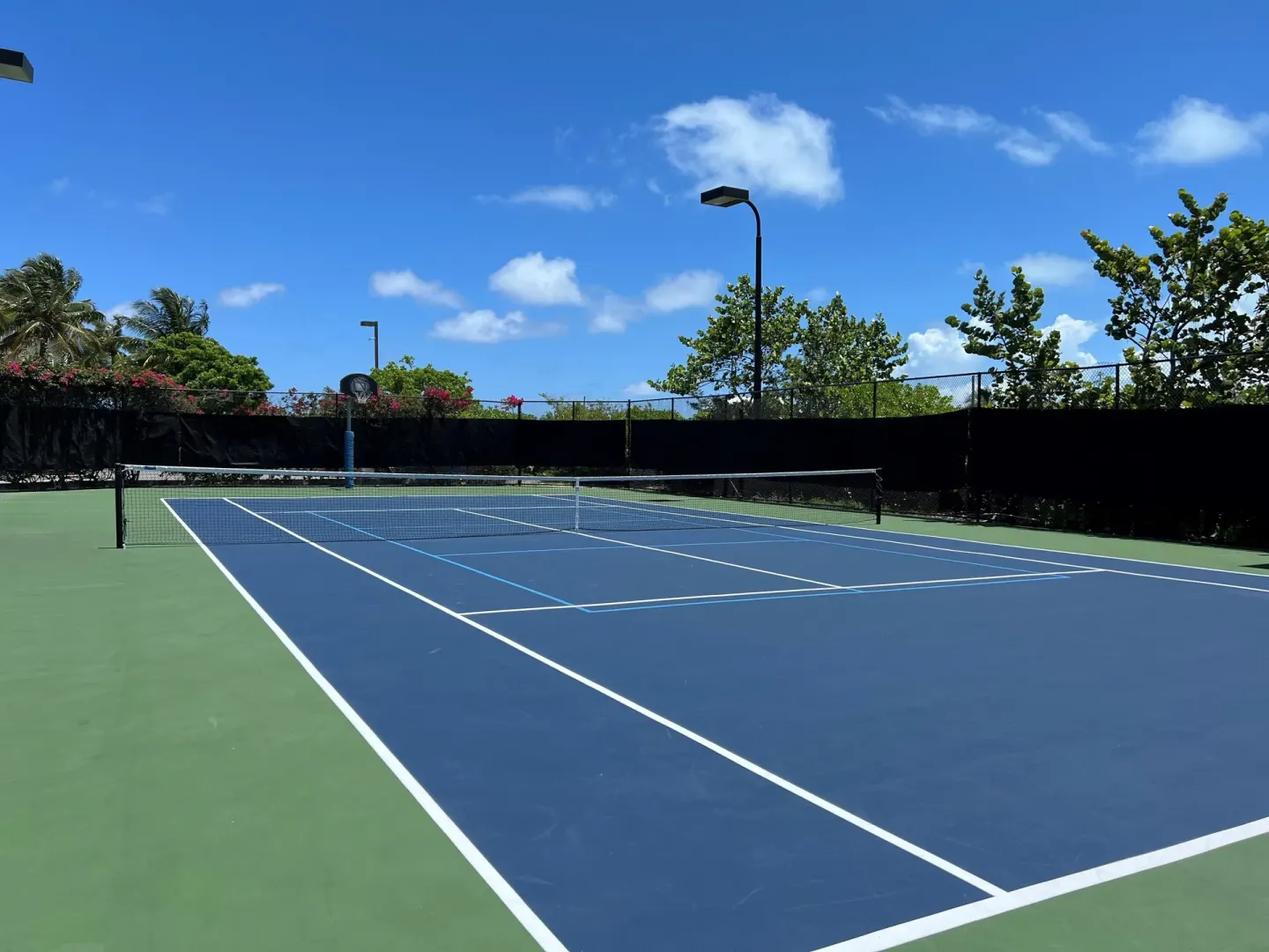 A blue and green tennis court sits under a bright sky at The Sands at Grace Bay.