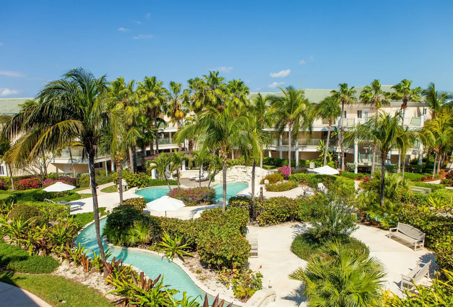 Tropical garden paths, palms, and a winding pool at The Sands at Grace Bay.