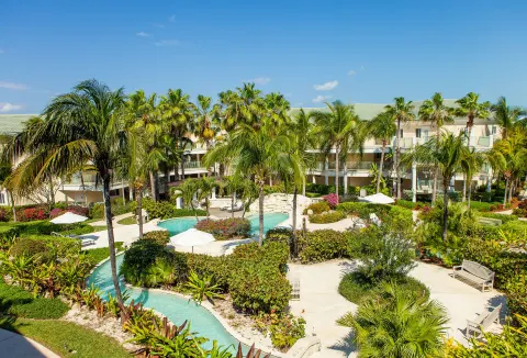 Tropical garden paths, palms, and a winding pool at The Sands at Grace Bay.