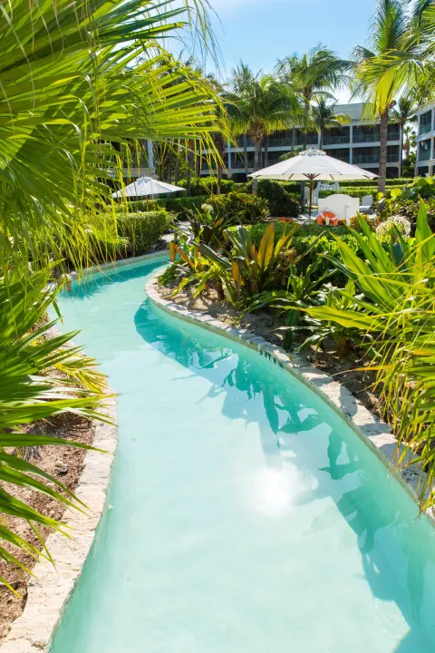 Narrow winding pool channel through tropical gardens at The Sands at Grace Bay.