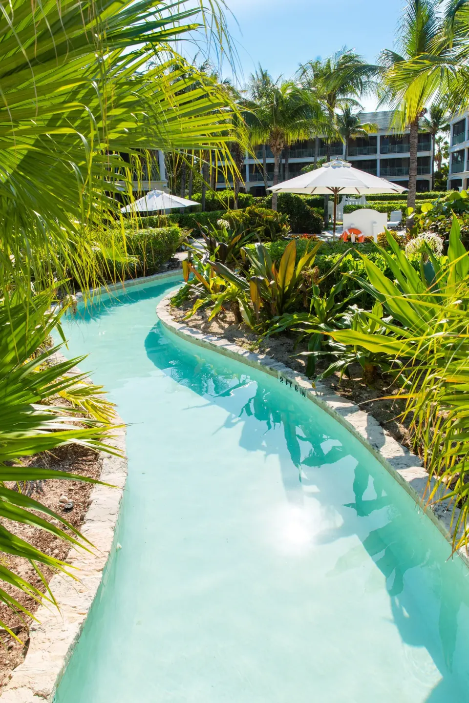 Narrow winding pool channel through tropical gardens at The Sands at Grace Bay.