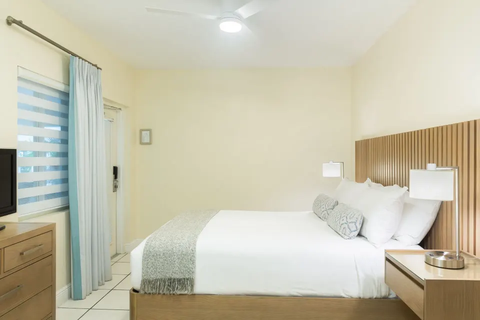 Junior Suite king bed with wood headboard and window at The Sands at Grace Bay.