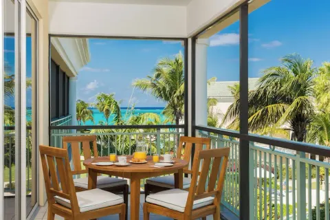 Furnished balcony with ocean and palm views at The Sands at Grace Bay.