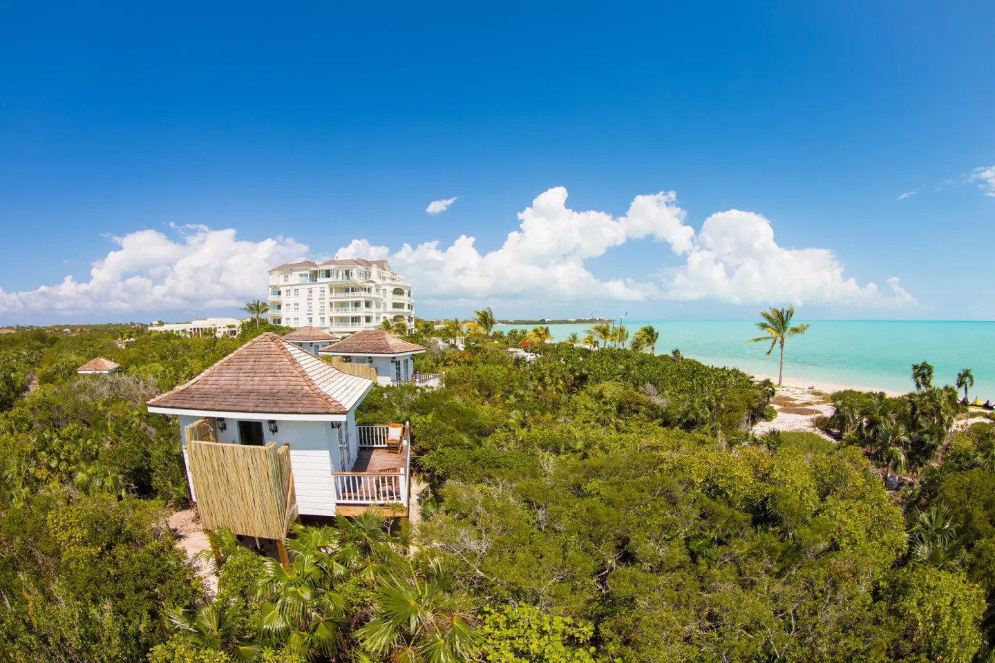 Aerial view of resort buildings, greenery, beach, and turquoise water at The Shore Club Turks and Caicos.