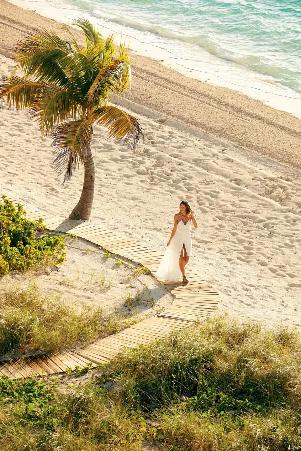 Woman walking a beach boardwalk at The Shore Club Turks and Caicos.