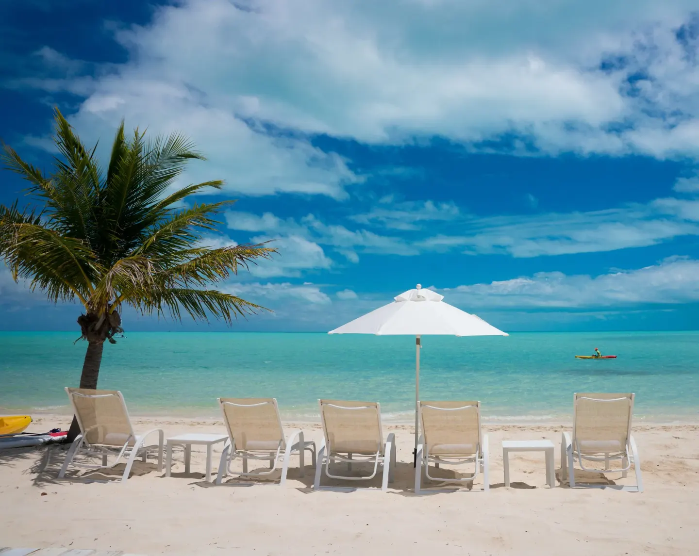 Beach loungers and umbrella facing turquoise water at The Shore Club Turks and Caicos.