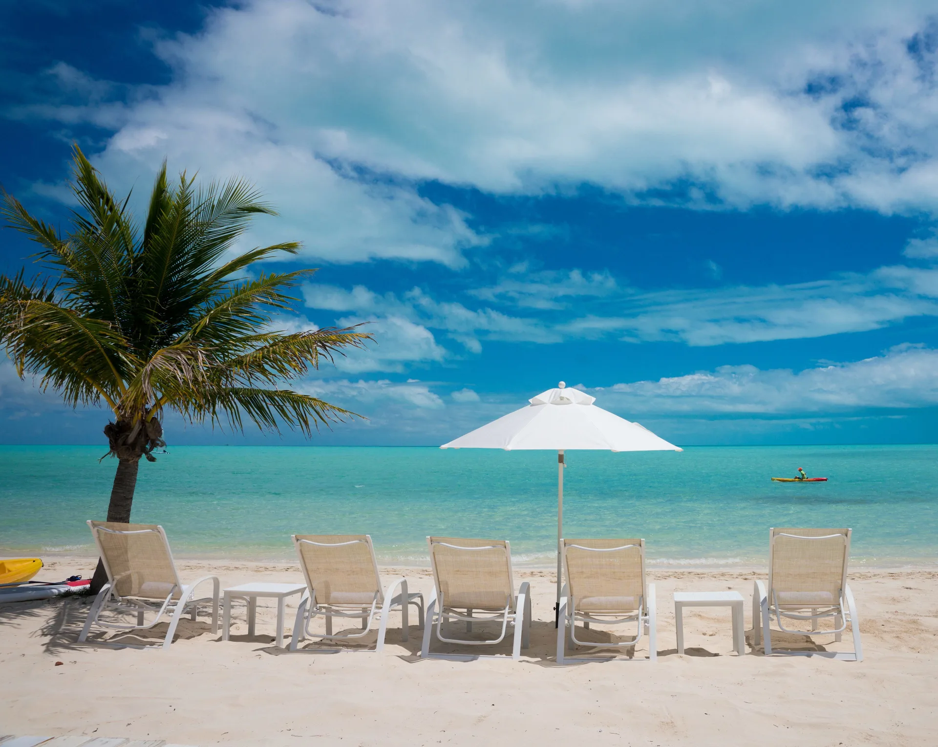 Beach loungers and umbrella facing turquoise water at The Shore Club Turks and Caicos.