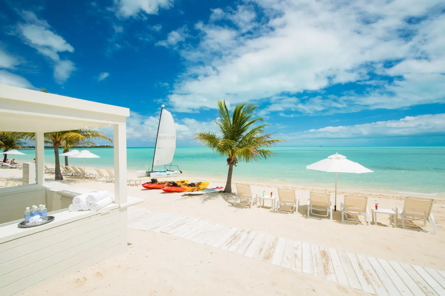Beach loungers, umbrellas, kayaks, and a sailboat at The Shore Club Turks and Caicos.