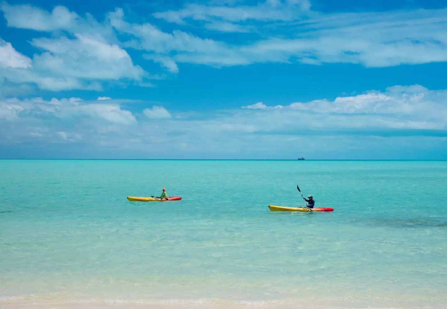 Two kayakers paddle in turquoise water off The Shore Club Turks and Caicos.