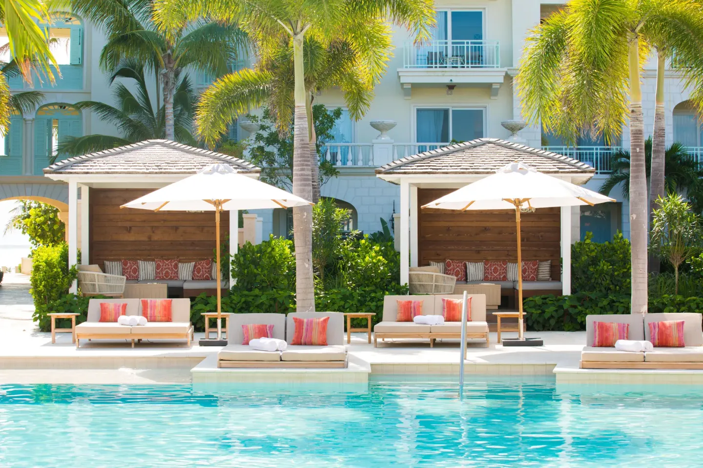 Pool loungers, umbrellas, and cabanas framed by palms at The Shore Club Turks and Caicos.