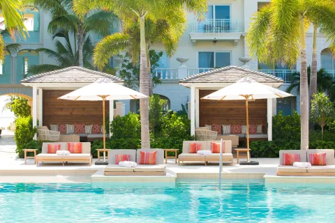 Pool loungers, umbrellas, and cabanas framed by palms at The Shore Club Turks and Caicos.