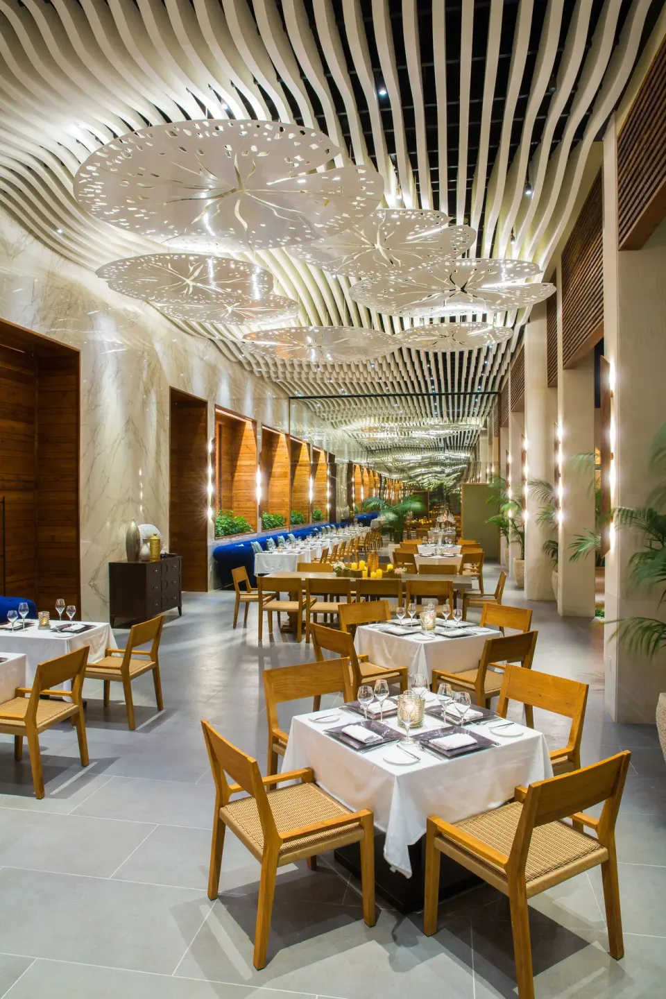 A long dining room with white tables and sculptural ceiling lights at The Shore Club Turks and Caicos.