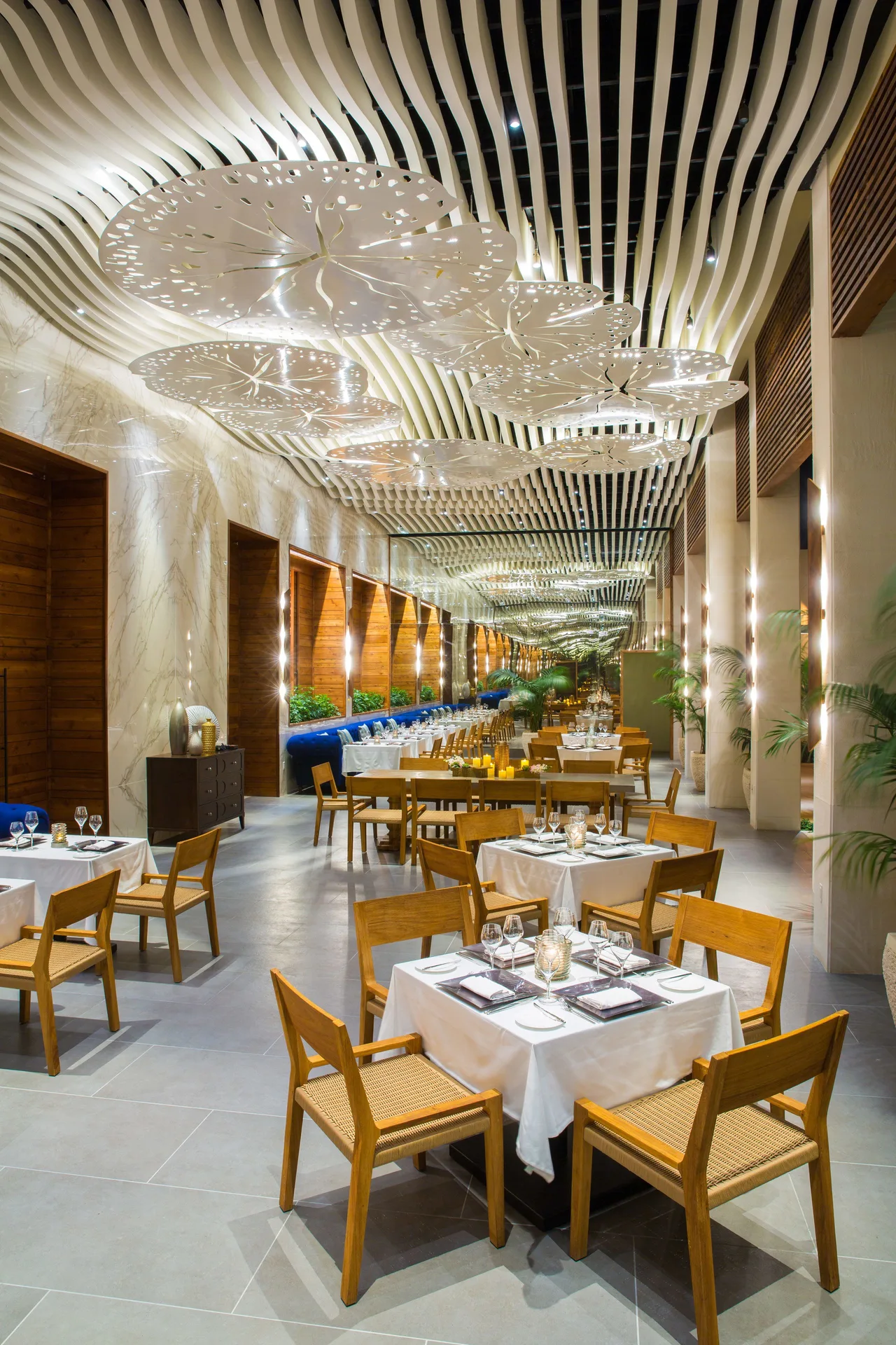 A long dining room with white tables and sculptural ceiling lights at The Shore Club Turks and Caicos.