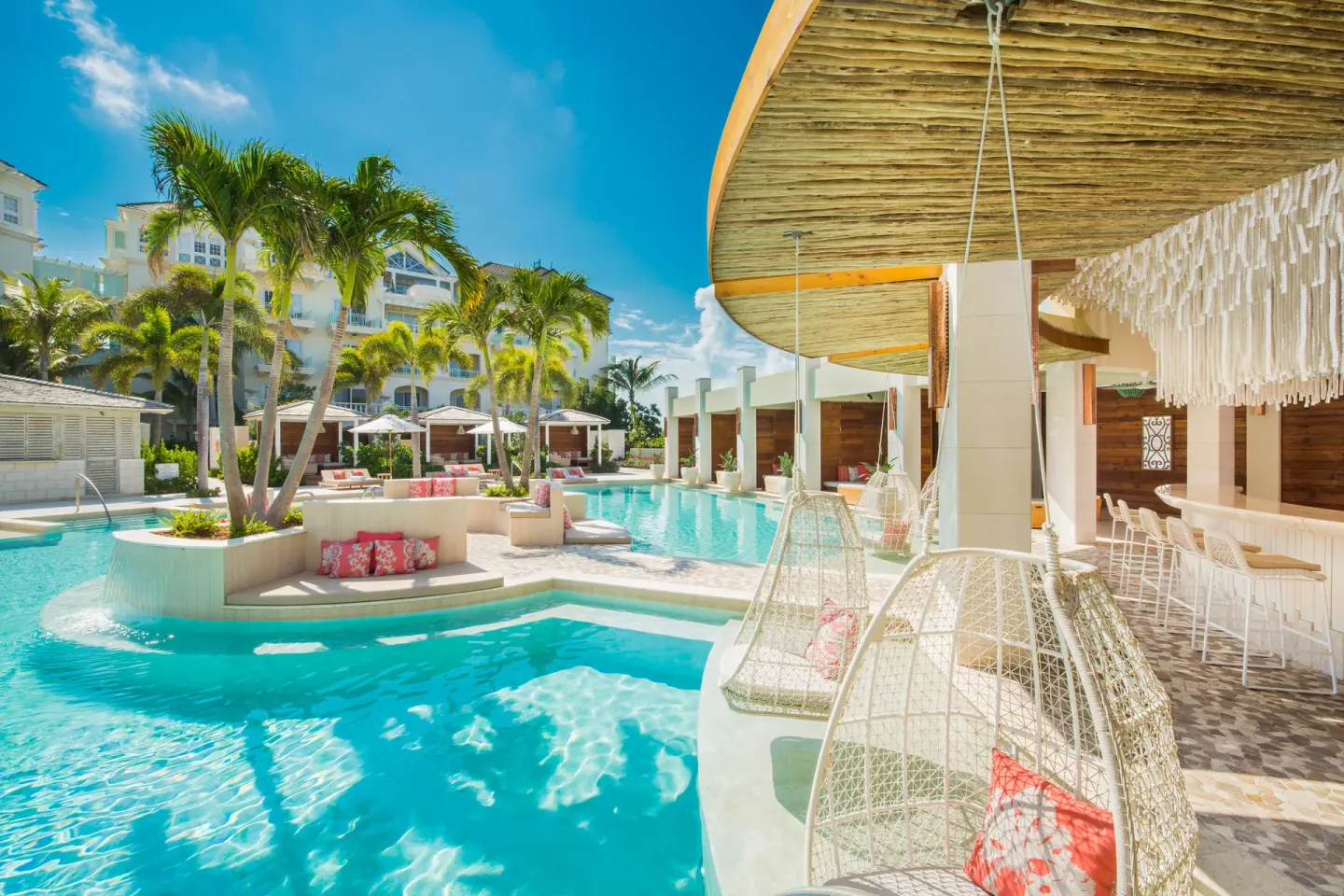Lagoon-style pool with hanging chairs and swim-up bar at The Shore Club Turks and Caicos.